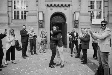 Two grooms hugging each other outside of the civil registry building.