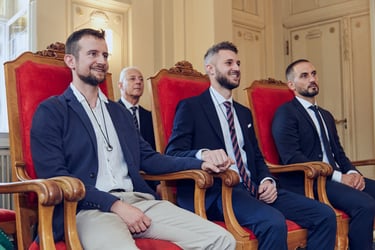 Grooms sitting on red chair during a civil wedding ceremony.