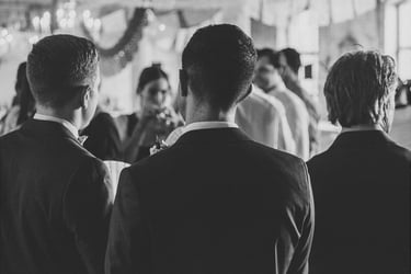 Three male wedding guests photographed from behind.