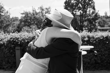 Wedding guest wearing a hat hugging the bride.