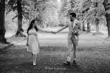 Bride and groom walking in a park holding hands.