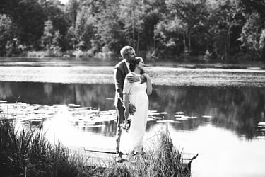 Bride and groom standing on a pier looking into the distance.