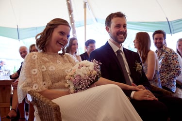 Married couple laughing at the speeches in a tent.