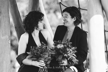 Two brides with bouquets looking at each other.