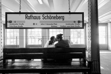 Newlywed couple kissing on a bench at the Rathaus Schönberg station.