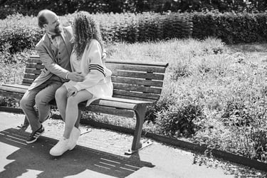 A young couple sitting on a bench in a park.