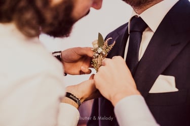 Best man fixing the groom's corsage to his lapel.