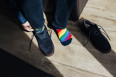 Der Bräutigam trägt Regenbogensocken und zieht seine Schuhe an.