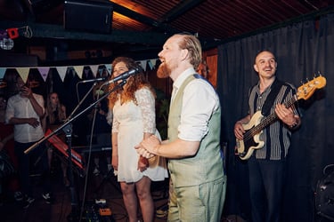 Bräutigam und Braut singen auf der Bühne während eines Hochzeitsempfangs.