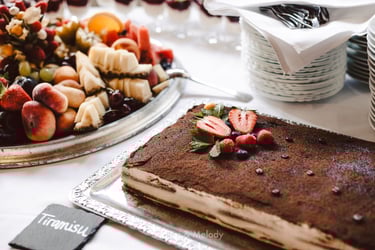 Ein Obstteller und Tiramisu werden auf einem Tisch serviert.