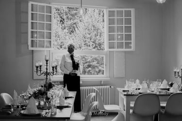 Waitress with a mask standing next to a window ready to serve wine.