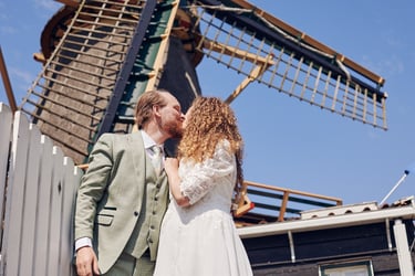 Bride and groom kissing in front of a wind mill.