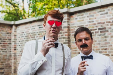 Two male wedding guests with photo booth accessories.