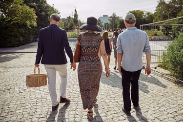 Three wedding guests walking on a cobbled path in Mauerpark.
