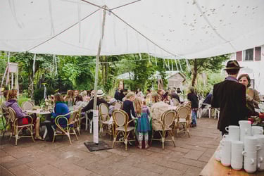 Wedding guests sitting at tables underneath a tarp.
