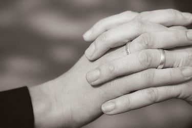 Clasped hands with wedding rings.