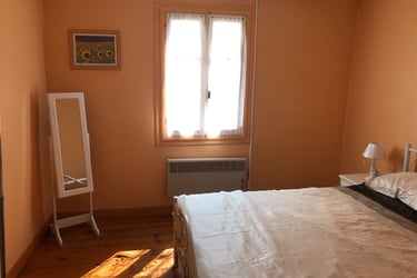 Sunny Quillan bedroom with orange walls, a floor mirror, and a large bed near a bright window.