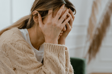 a woman in a sweater holding her hands to her face