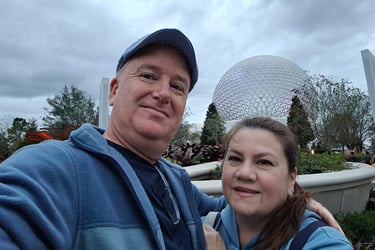 a man and woman taking a selfie in front of spaceship earth at Epcot