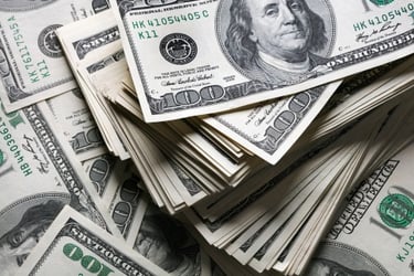 A thick stack of one hundred dollar bills featuring Benjamin Franklin on a background of US currency.