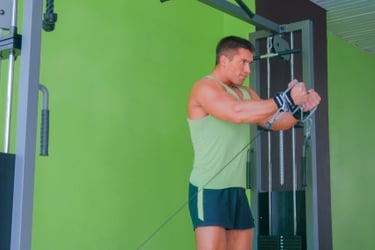 Muscular man performing a cable chest fly exercise on a gym machine for strength training.