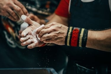 A weightlifter with wrist wraps applying white gym chalk to hands for a secure grip during a workout.