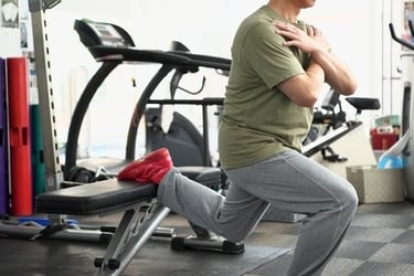 A man performing a Bulgarian split squat using a gym bench for leg strength training.