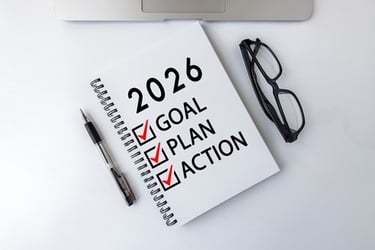 Spiral notebook with 2026 goal setting checklist including plan and action items on a white desk.
