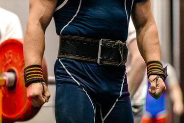 A powerlifter wearing a black leather weightlifting belt and wrist wraps while preparing for a squat.