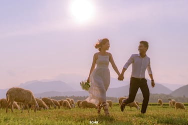 a man and woman holding hands while walking through a field