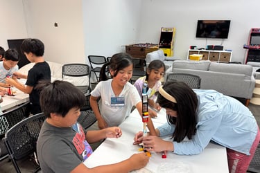 A group of kids in a team building the tallest tower out of a set of legos.