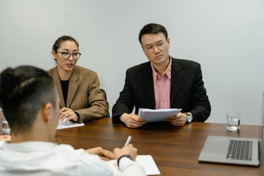 Three people in an office watching a person delivering a consultation service virtually 