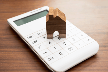 a calculator with a small wooden house on top