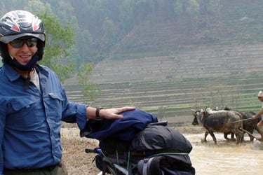 Backpacker with a motorcycle and waterbuffalo in the background