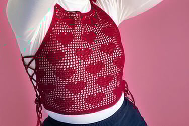 a woman with a red heart design crochet shirt on top of a white shirt