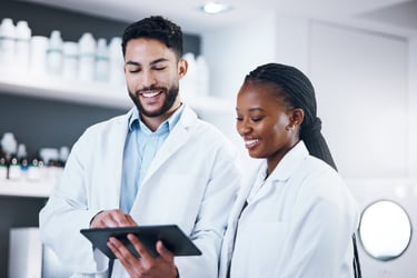 A male pharmacist and female pharmacist looking at a tablet