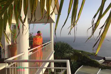 Bruno Meireles in orange robe standing on balcony of Indigo Star House