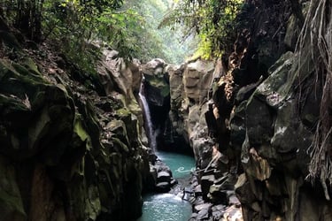 Kolam alami Curug Cikuluwung yang berwarna hijau kebiruan dikelilingi tebing batu sedimen vertikal dan sempit, menunjukkan pe