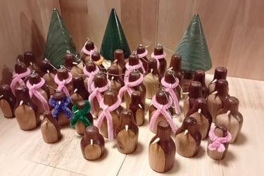 A group of turned wooden penguins in dark wood with light front and light beak. Some wearing pipecleaner scarfs