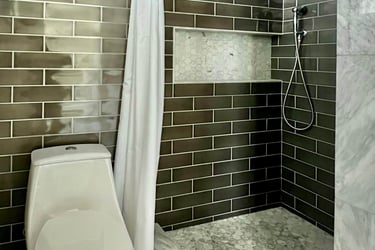 A bathroom with marble floor tile, and full height grey subway wall tile.