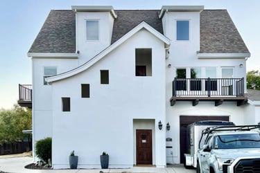 A French Revival architecture home with sloping roof lines, high dormers, and cantilevered decks.