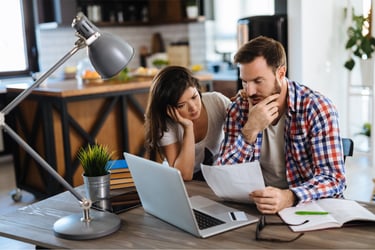 Casal  trabalhando junto ao notebook, com semblante frustrado por não estar conseguindo resultados