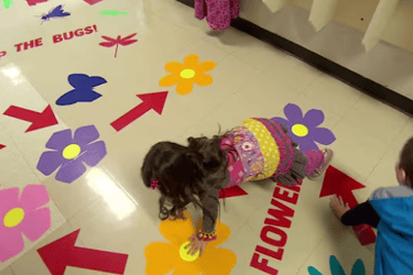 two children playing on a floor with bright flower images