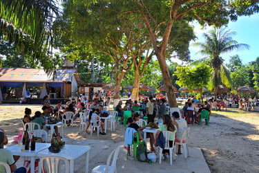 Crowd dining outdoors under palm trees under the shade at Centro Recreacional Mokanranko