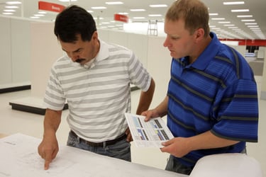 Two technicians in a retail setting reviewing printed documents together.