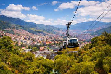 A scenic view of the Sarajevo cable car ascending over lush trees with a panoramic city landscape and mountains.
