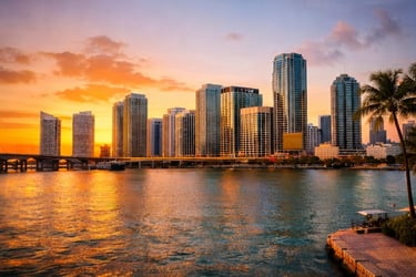 Golden sunset over the Miami skyline skyscrapers and waterfront with a bridge and palm trees.