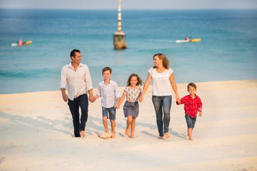 A family of five walk across Cottesloe Beach in a portrait by Fisher Photography