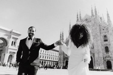 a man and woman holding hands and walking through in Milan Piazza Duomo