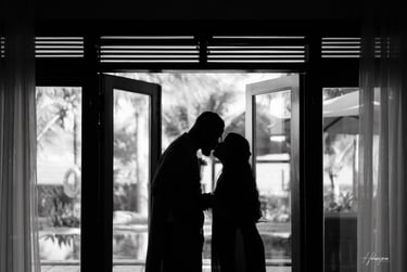 a couple kissing in front of a large window